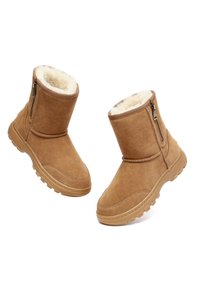 Tan-farbene Wildleder-Ankelstiefel mit Kunstfellfutter, Reißverschlussdetails an der Seite und strukturiertes Gummifleck für besseren Halt. Runde Zehenpartie und dekorative Steppnähte.