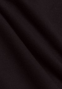 Zwarte gebreide stof met een gladde textuur, die subtiele ribbels vertoont. Het materiaal lijkt zacht en flexibel, met gedrapeerde plooien.