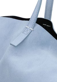 Borsa tote in suede blu chiaro con una texture morbida, caratterizzata da un design semplice e da spalline sottili, che mostra un interno pulito e non foderato.