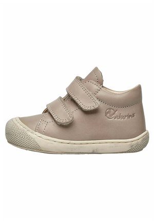 Chaussure en cuir beige clair avec deux bandes Velcro, bout arrondi, semelle en caoutchouc texturée et logo en relief sur le talon.