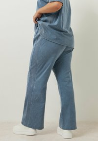 Ljust blå denimbyxor med rak bendesign, som har en subtil blekt textur, sidssämmar och en avslappnad passform. Matchat med vita sneakers.