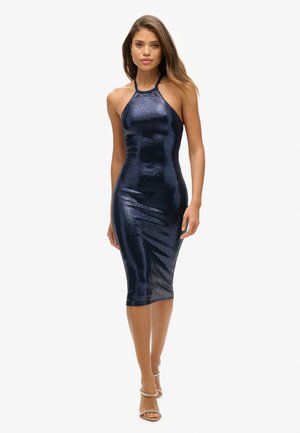 Marineblaue Pailletten-Midi-Kleid mit Halterneck-Design, figurnaher Silhouette und glatter Textur. Das Model trägt nacktfarbene, geschnürte High Heels.