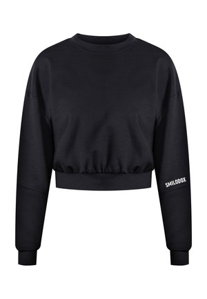 Musta lyhythihainen collegetakki, jossa on pitkät hihat, ribbineulehihansuut ja kerroksittain laskostettu helma. Vasemmassa hihassa on valkoista "SMILODOX" -tekstiä. Sileä pinta.