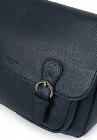 Borsa in pelle blu scuro con superficie texturizzata. Presenta una chiusura con pattina e un accento di fibbia metallica sulla tracolla. Branding minimale visibile.