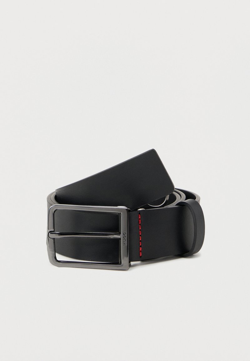 Μαύρη δερμάτινη ζώνη με ασημένια μεταλλική αγκράφα. Διαθέτει λεία υφή και κόκκινη ραφή κοντά στην αγκράφα. Κλασικός και μίνιμαλ σχεδιασμός.