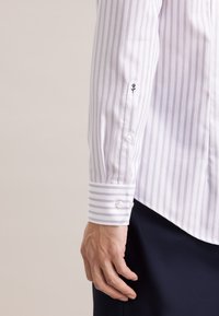 Wit en lichtgrijs gestreept overhemd met een puntige kraag, knoopmanchetten en een klein zwart bloemrijk borduursel op de mouw.