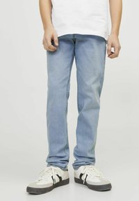 Jeans de mezclilla azul claro con un corte de pierna recta, usados con zapatillas blancas y grises con detalles en negro. Diseño minimalista, sin patrones visibles.