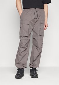 Šedé cargo kalhoty s elastickým pasem, nastavovacím stahovacím páskem a několika bočními kapsami. Vyrobeno z lehké texturované látky.