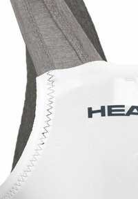 Brasile sportivo bianco con spalline grigie, caratterizzato da un tessuto testurizzato, cuciture piatte e un logo stampato "HEAD" in grigio scuro sulla parte anteriore.