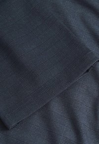 Tessuto blu navy con un delicato motivo a griglia, caratterizzato da una superficie fine e liscia. Leggero e adatto per capi su misura.