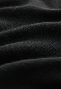 Tissu noir avec une surface douce et texturée, présentant des plis visibles et une apparence lisse mettant en avant sa légèreté et sa qualité tactile.