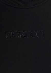 Tissu noir avec logo "FIORUCCI" embossé centré sous un col côtelé.