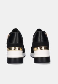 Zapatillas negras con un acabado de piel suave, acentos de herrajes dorados, una media suela blanca y una suela exterior texturizada negra, con cierre de cremallera.