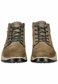 Botas de tobillo de ante marrón con cierre de encaje negro, suelas de goma crema contrastantes y acabado texturizado. Diseño robusto pero flexible.