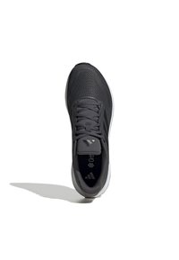 Zapatilla deportiva gris con parte superior de malla texturizada, cierre de cordones, lengüeta acolchada y suela blanca en contraste. Logo visible en la parte superior.