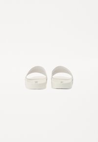 Sandale albe tip slip-on cu un finisaj mat, neted, având două curele curbate și o talpă groasă. Design minimalist fără logo-uri vizibile.