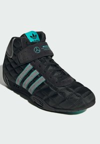 Čierne vysoké tenisky s prešívanou textúrou, tyrkysovými akcentami, tromi striebornými pruhmi a suchým zipsom. Majú gumovú podrážku a branding.