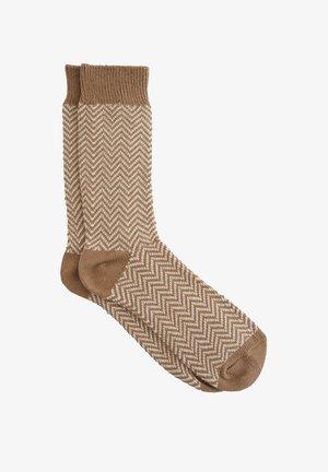 Calzini a motivo spigato marrone con una fascia a coste e una consistenza morbida. Il design presenta linee zigzag bianche su una base marrone.