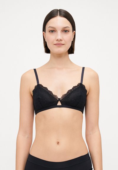 Brassière en dentelle noire avec des bonnets triangulaires, présentant un délicat bord festonné, des bretelles ajustables et un détail en forme de clé au centre.
