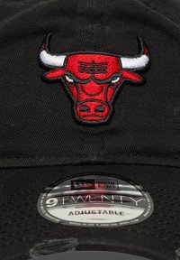 Black cap made from fabric featuring a red embroidered bull logo on the front. Adjustable strap with New Era branding on the inner tag.