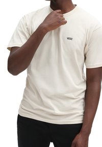 Krämfärgad bomulls-t-shirt med rund hals och korta ärmar, med en liten svart "VANS"-logotyp på bröstet.