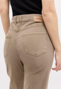 Helle braune hochgeschnittene Jeans aus weichem Stoff, mit zwei Gesäßtaschen und einem sichtbaren Leder-Logopatch mit der Aufschrift "ANGELS."