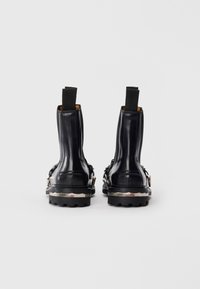 Bottines en cuir noir avec des panneaux élastiques sur les côtés et des accents en métal argenté. Semelle plateforme texturée avec une semelle robuste.