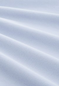 Tessuto azzurro chiaro con una texture liscia, che mostra morbide pieghe e un sottile motivo di trama. La superficie appare uniforme e omogenea.