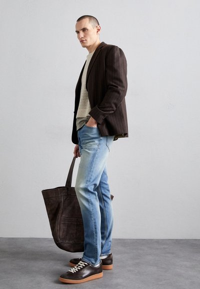 Brown pinstripe blazer, cream textured knit sweater, light blue jeans, brown leather shoes with white laces, and a dark leather tote bag.