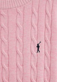 Jersey de punto cable rosa con logo bordado en negro de una persona llevando un palo de golf en la zona del pecho.