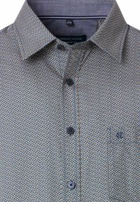 Patterned button-up shirt made from woven fabric, featuring a blue base with small geometric shapes in yellow and white, and a chest pocket.