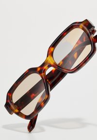 Brown tortoiseshell sunglasses with a bold rectangular shape, featuring a thick frame and light-colored lenses.
