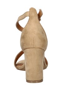 Beige suède hoge hak sandaal met enkelbandje en blokhak, vanaf de achterkant weergegeven op een effen witte achtergrond.