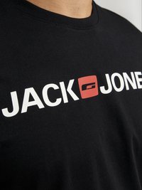 Zwarte katoenen t-shirt met een ronde hals en korte mouwen, met vetgedrukte witte letters "JACK" en "JONES," met een rood accent vierkant.