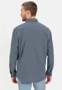Langdonige geruite shirt met een blauw-zwart patroon, knopenmanchetten en een klassieke kraag. De stof lijkt lichtgewicht en gestructureerd te zijn.