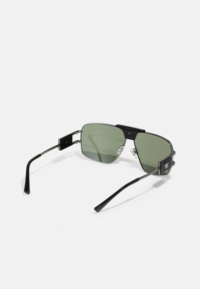 Lunettes de soleil avec des verres verts, monture rectangulaire noire, accents argentés et branches en métal. Détail notable : logo sur le côté.