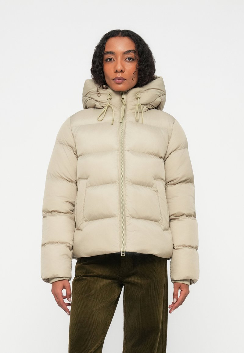 Chaqueta acolchada beige con capucha ajustada, cremallera frontal y cordones elásticos. Presenta secciones acolchadas y bolsillos laterales.