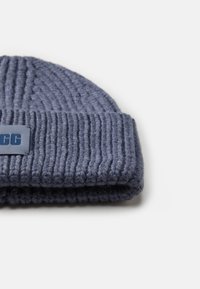 Bonnet en laine bleu marine tricoté avec une texture côtelée et un revers. Comprend un petit patch logo de couleur contrastante.