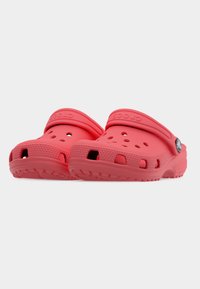 Paire de sabots Crocs rouges avec des trous de ventilation, des brides ajustables au talon et des semelles texturées sur un fond blanc uni.