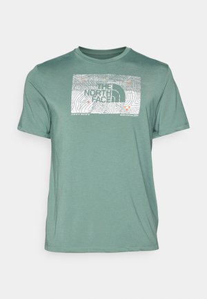 T-shirt verde a maniche corte realizzato in tessuto morbido con un design grafico bianco caratterizzato da linee di contorno e testo "THE NORTH FACE".