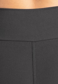 Svart leggings med hög midja, tillverkad av mjukt, stretchigt tyg med en slät midjereså och förstärkta sömmar längs med sidorna.