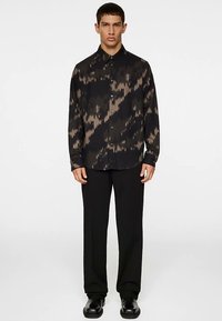 Svart skjorta med tonalt abstrakt mönster, knappslå, långa ärmar och klassisk krage, kombinerad med svarta byxor och skor.