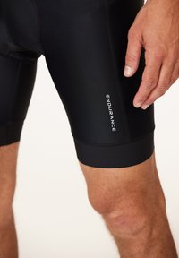 Svarta cykelshorts i elastiskt material, med en tät passform, slät yta och en synlig logotyp på sidan.