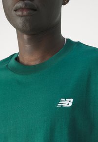 Groene katoen t-shirt met een ronde hals en korte mouwen, met een witte geborduurde New Balance logo op de linkerborst.