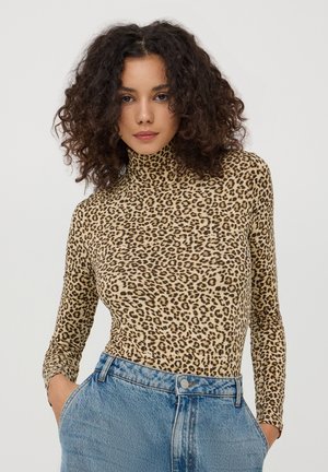 Maglione a collo alto con stampa leopardata realizzato in tessuto elastico, con maniche lunghe e silhouette aderente, abbinato a jeans a vita alta.