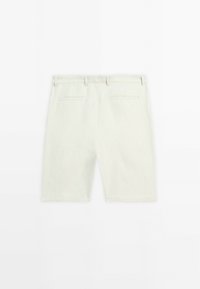 Shorts en lin vert clair avec une coupe décontractée, présentant deux poches arrière et des passants de ceinture. Texture lisse et design épuré et simple.