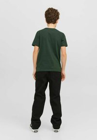 Grøn kortærmet T-shirt lavet af bomuldsstof, parret med sorte bukser. T-shirten har en rund halsudskæring; bukserne har et lige ben-design.
