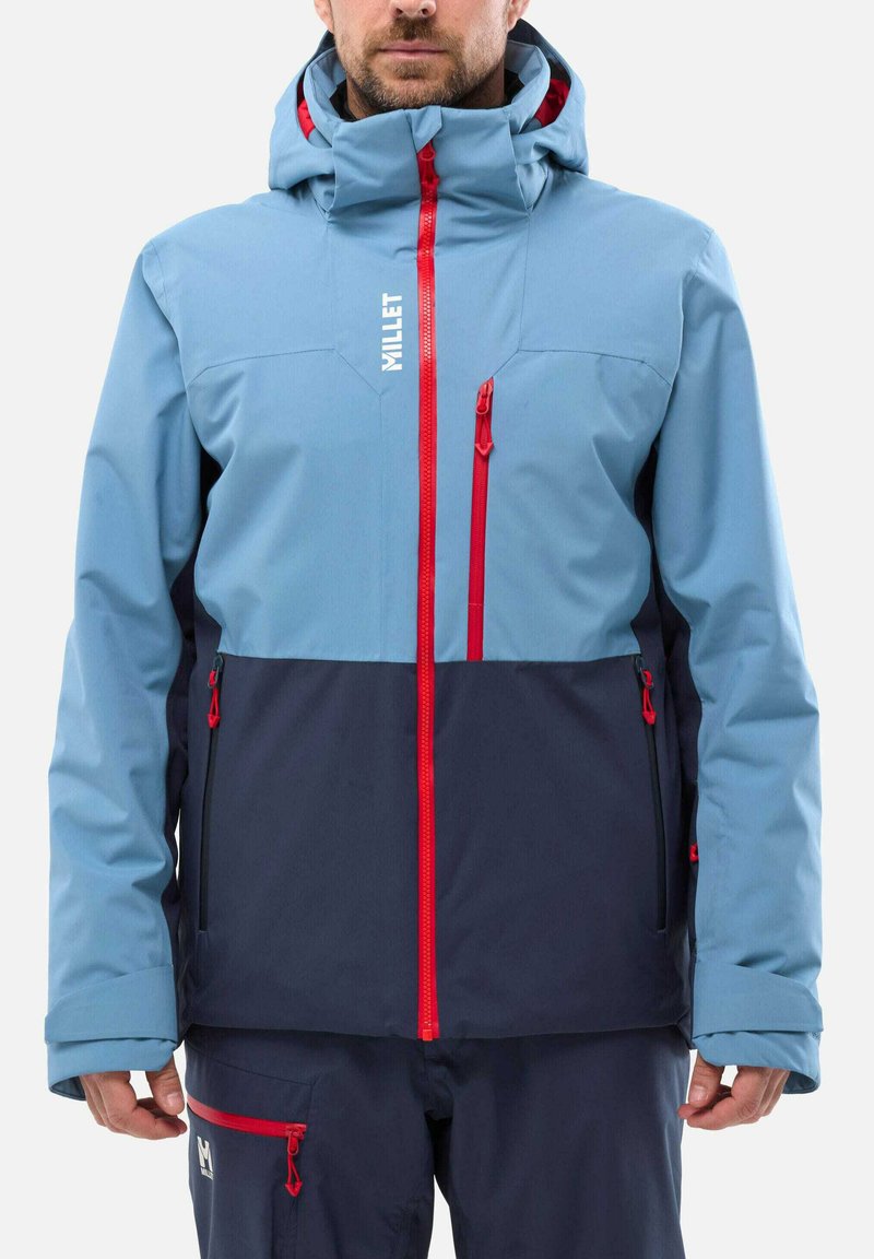 Sky blue and navy ski jacket with a high collar, red zippers, and multiple pockets. Features waterproof material and adjustable hood.