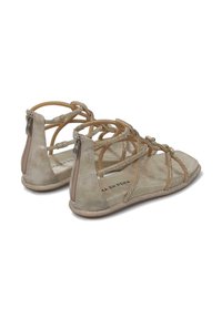 Sandalias de ante gris claro con correas decorativas, cierre con cremallera en la parte posterior y suela plana. Presentan sutiles acentos metálicos y una plantilla acolchada.