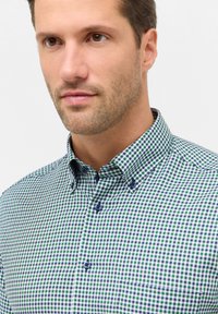 Geruit overhemd met een patroon van groene en marineblauwe vierkanten, met een button-down kraag, blauwe knopen en een borstzak.